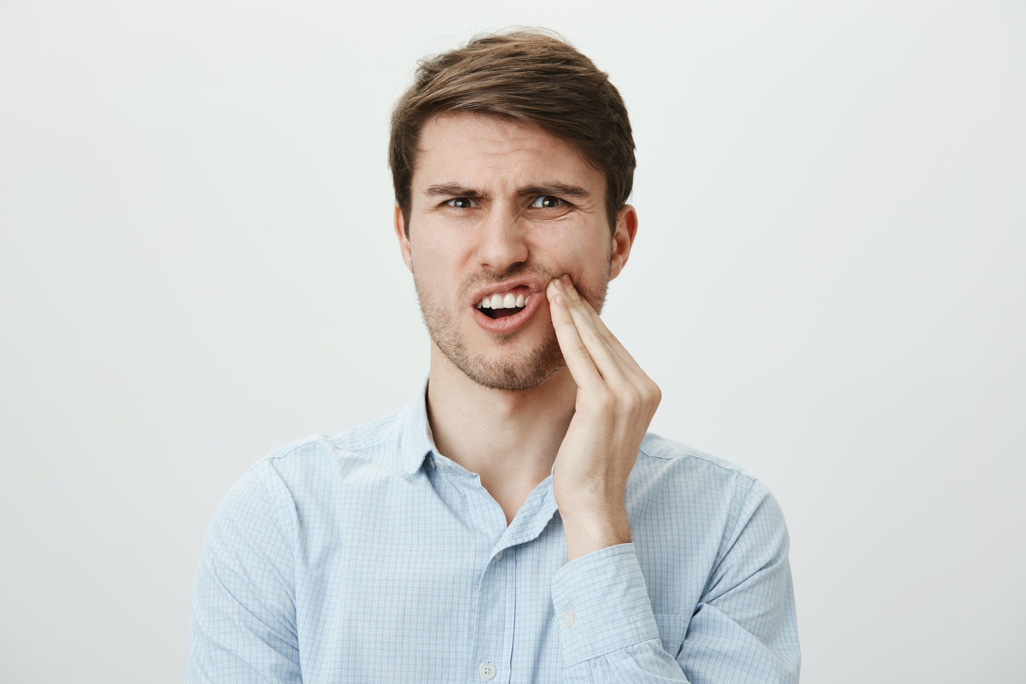 Dental and health concept. Portrait of bothered attractive european model holding hand on tooth