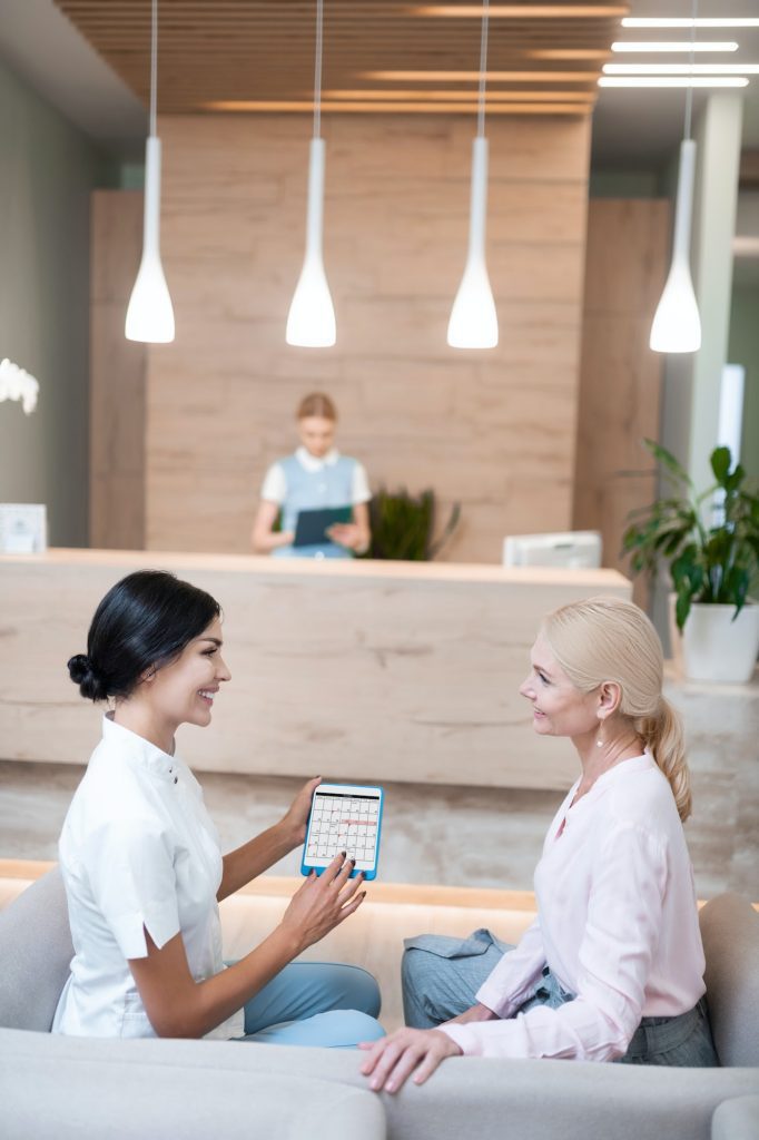 Dentist offering her patient the date of their next appointment